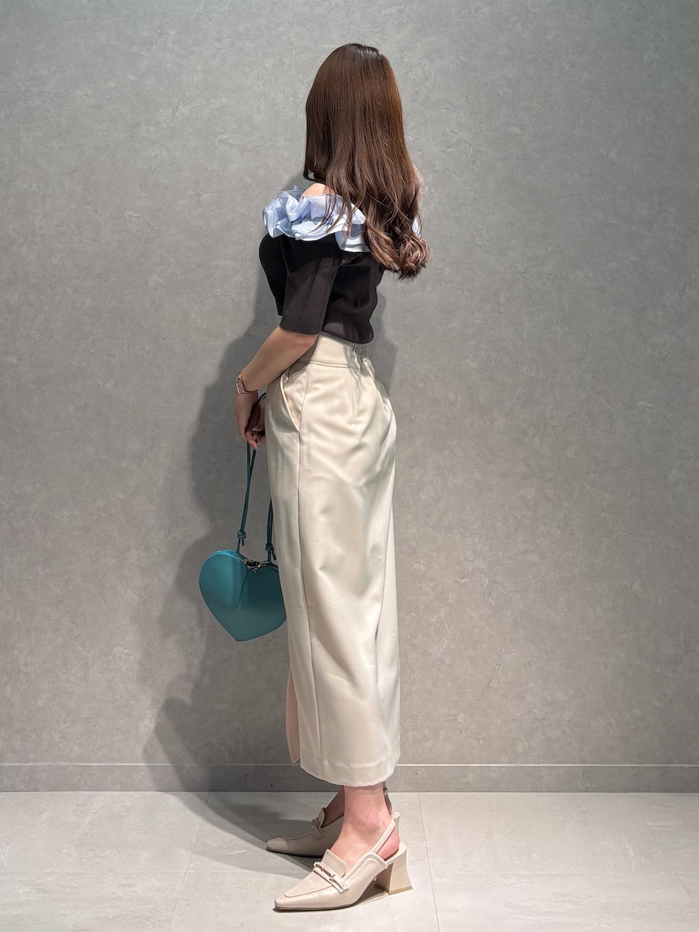 ホワイト系のスカート、グレー系のニット/セーター、グリーン系のショルダーバッグを着用したレディースの春コーディネートの4枚目の写真
