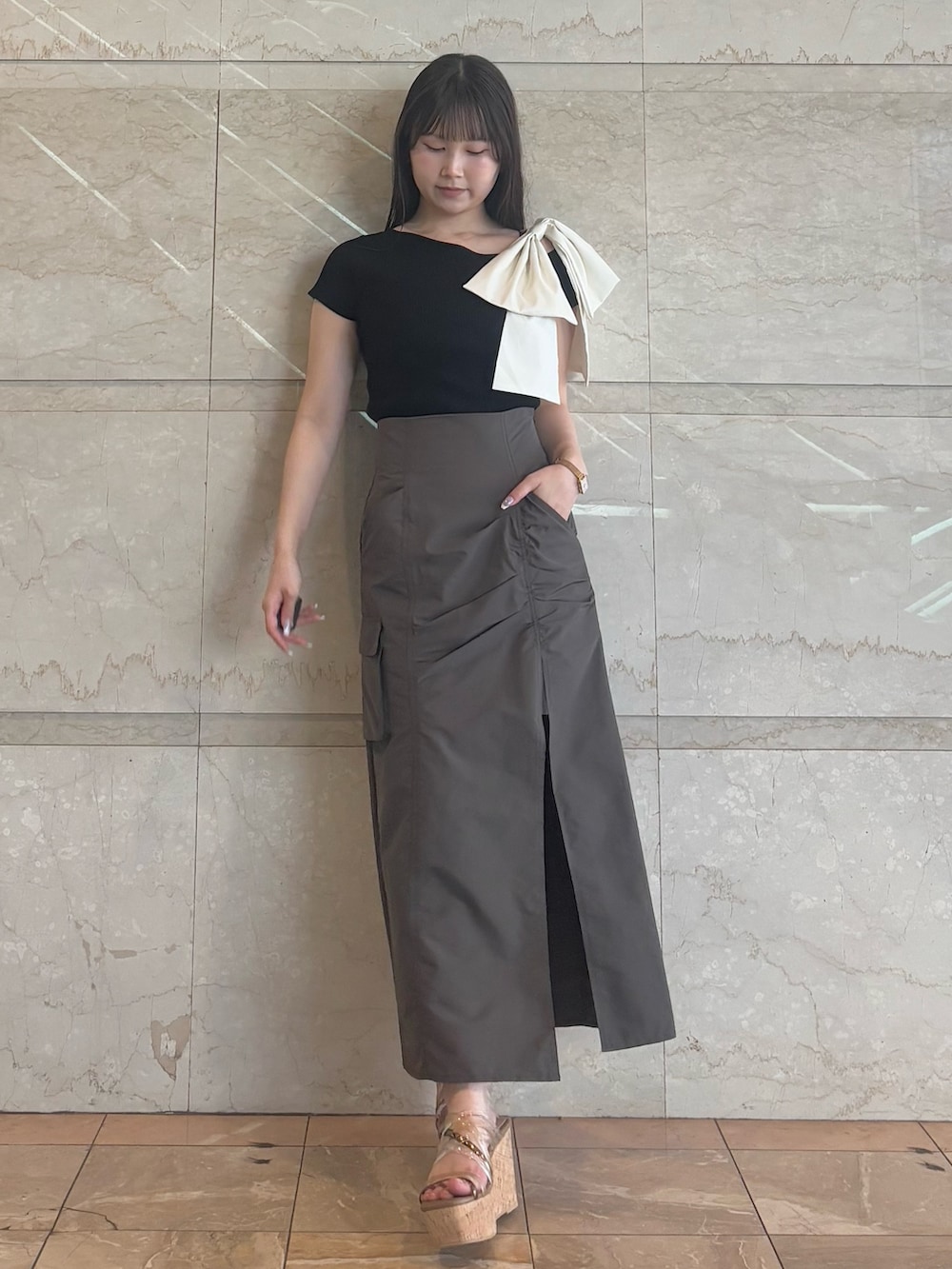 ブラウン系のスカート、ブラウン系のサンダル、ブラック系のニット/セーターを着用したレディースの夏コーディネートの6枚目の写真