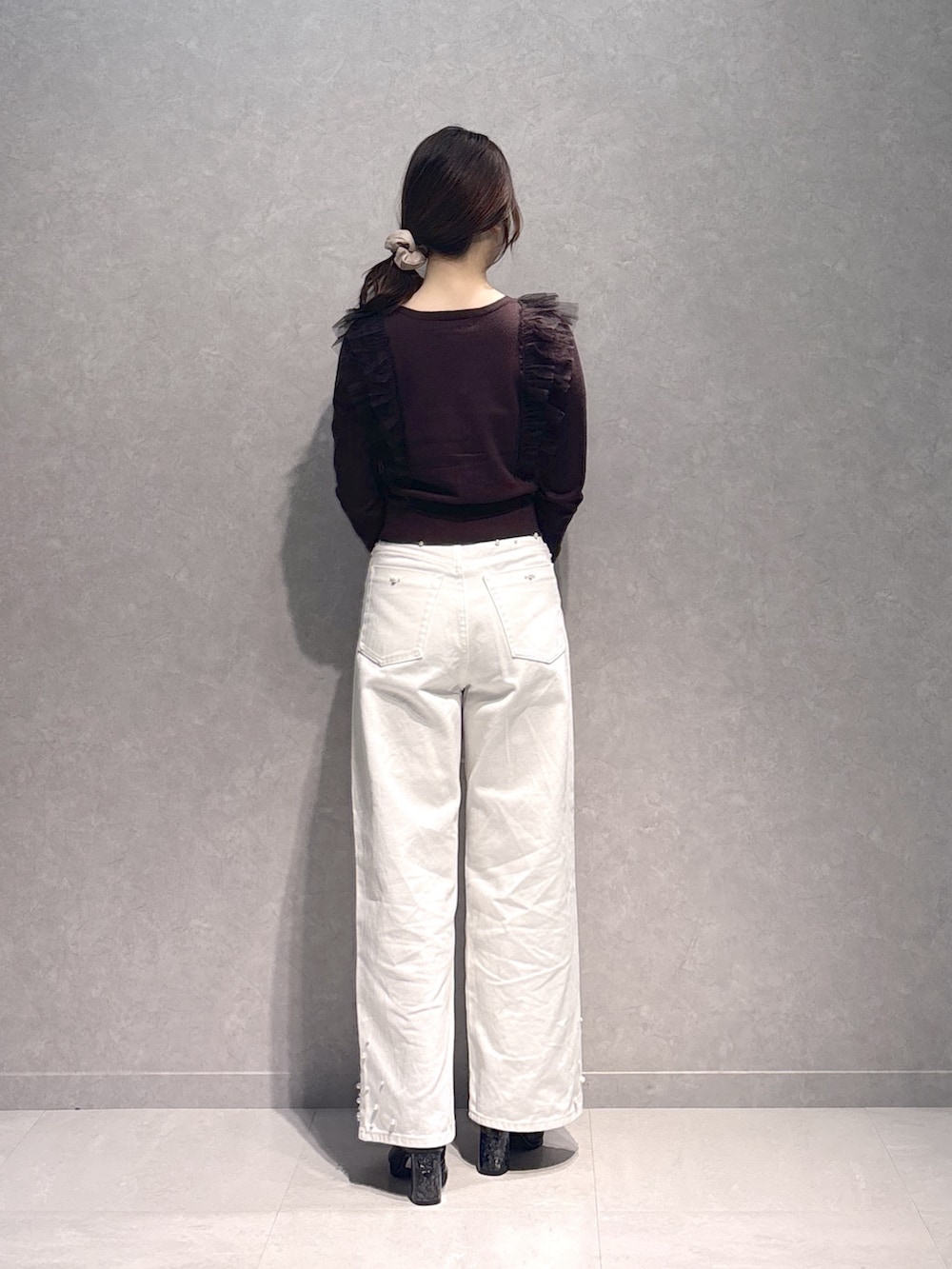 ホワイト系のデニムパンツ、ブラウン系のニット/セーター、ホワイト系のハンドバッグを着用したレディースの秋コーディネートの5枚目の写真