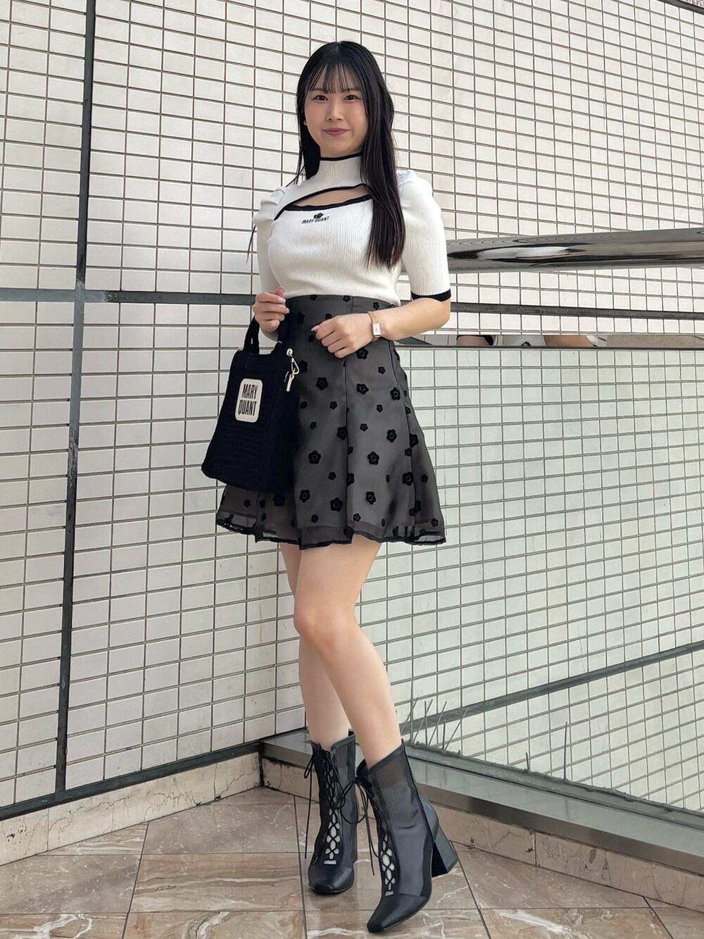 ブラック系のスカート、ブラック系のブーツ、ホワイト系のニット/セーターを着用したレディースの春コーディネートの7枚目の写真