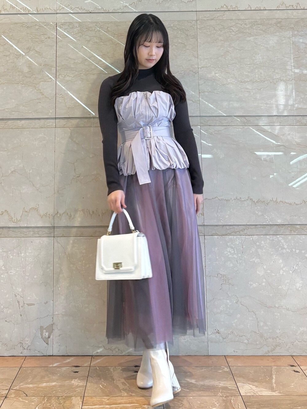 パープル系のワンピース、ホワイト系のブーツ、ピンク系のハンドバッグを着用したレディースの冬コーディネートの2枚目の写真