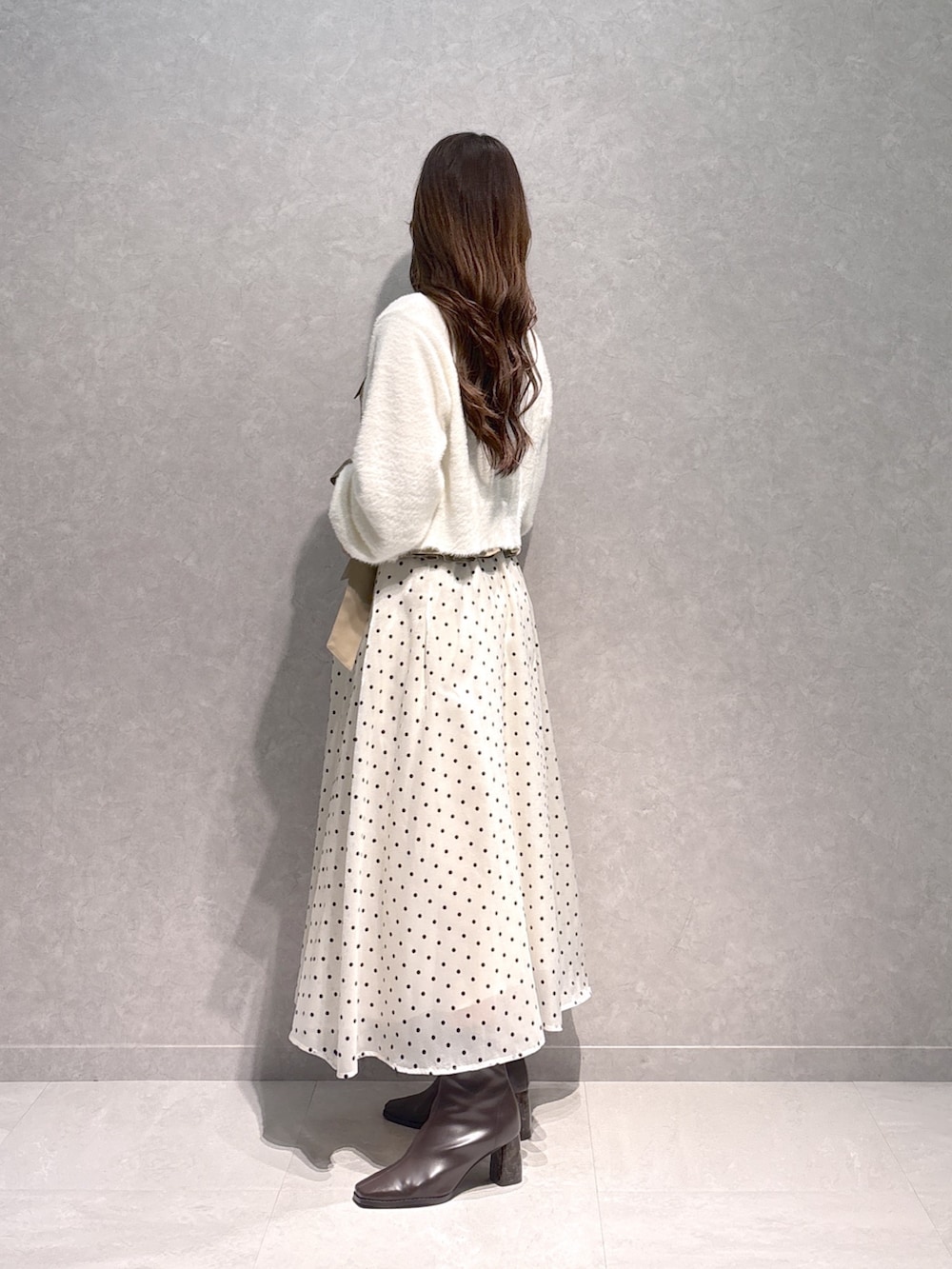 ベージュ系のワンピース、ホワイト系のカーディガン/ボレロ、ブラウン系のブーツを着用したレディースの秋コーディネートの3枚目の写真