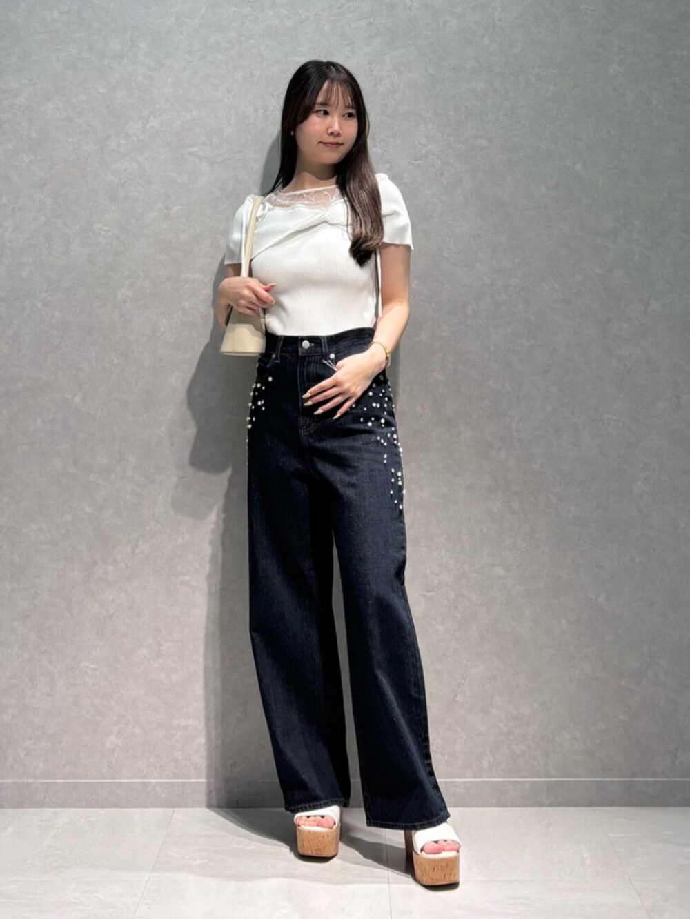 ホワイト系のサンダル、ホワイト系のハンドバッグ、ブルー系のデニムパンツを着用したレディースの夏コーディネートの2枚目の写真