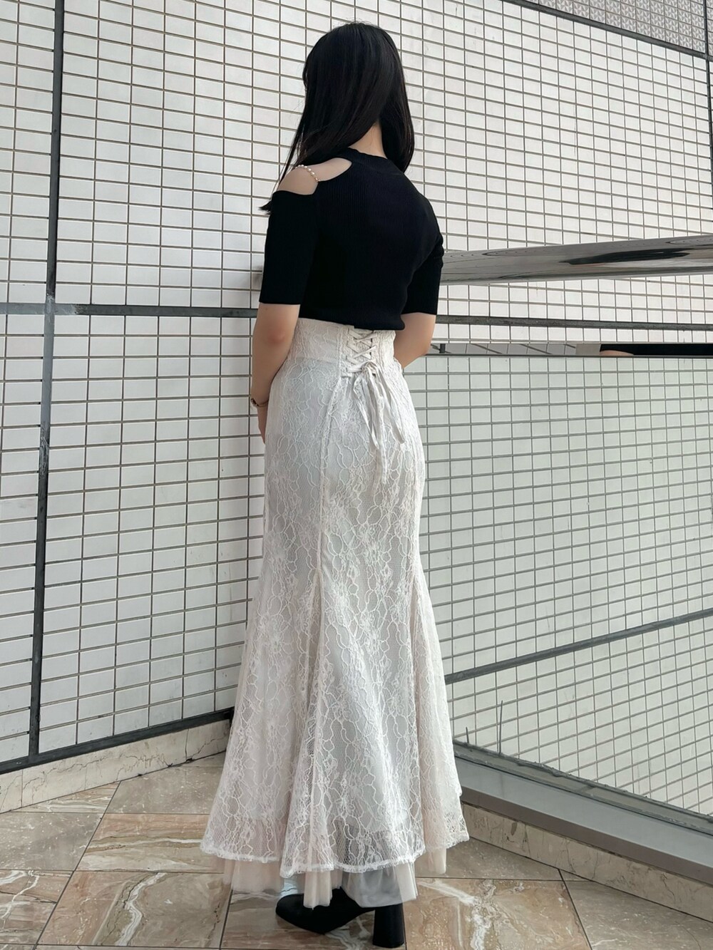 ホワイト系のスカート、ブラック系のブーツ、ブラック系のニット/セーターを着用したレディースの秋コーディネートの3枚目の写真