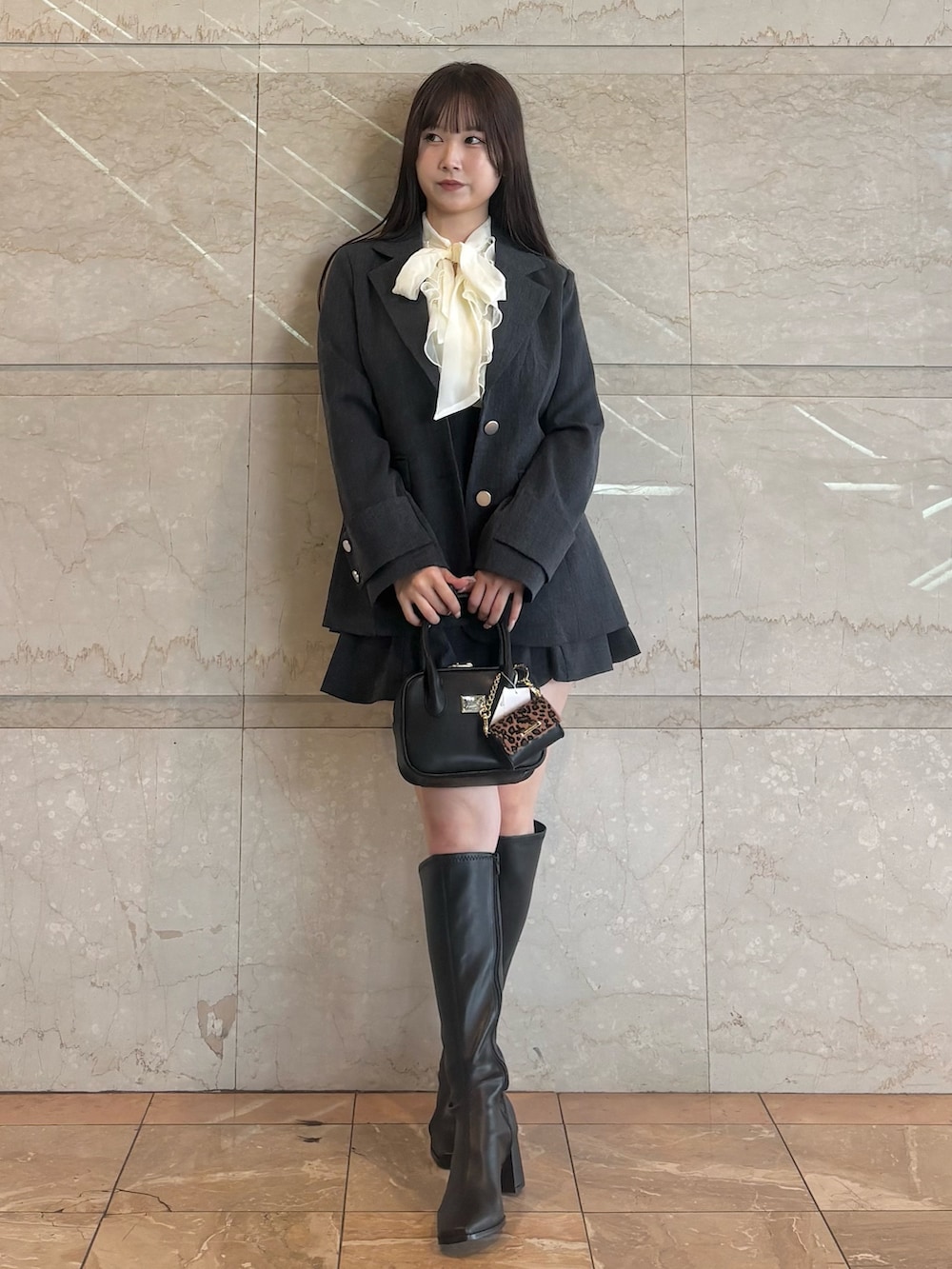 グレー系のスカート、ホワイト系のシャツ/ブラウス、ブラック系のハンドバッグを着用したレディースの秋コーディネートの2枚目の写真