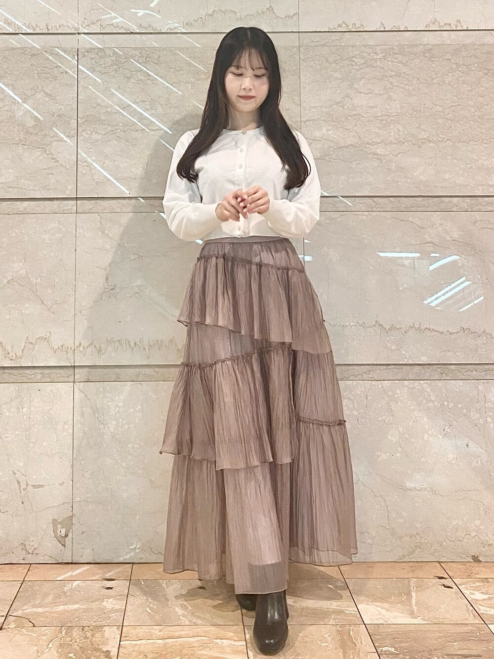 ブラウン系のスカート、ホワイト系のカーディガン/ボレロ、ブラウン系のブーツを着用したレディースの冬コーディネートの2枚目の写真