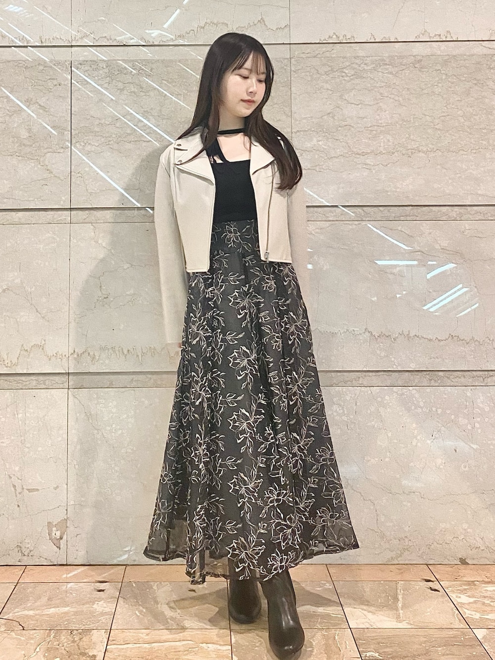 グレー系のスカート、ブラック系のニット/セーター、ホワイト系のライダースジャケットを着用したレディースの冬コーディネートの3枚目の写真