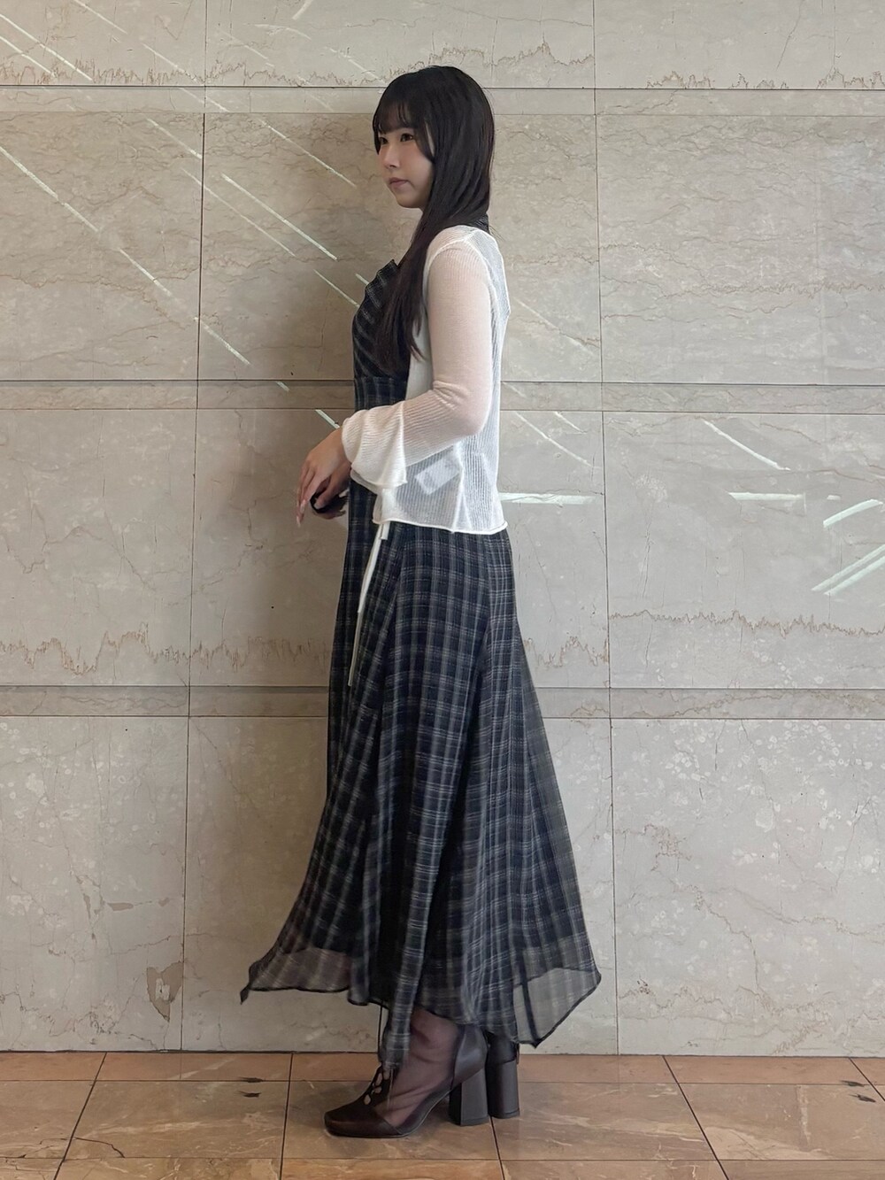 ブラック系のワンピース、ホワイト系のカーディガン/ボレロ、ブラウン系のブーツを着用したレディースの夏コーディネートの3枚目の写真