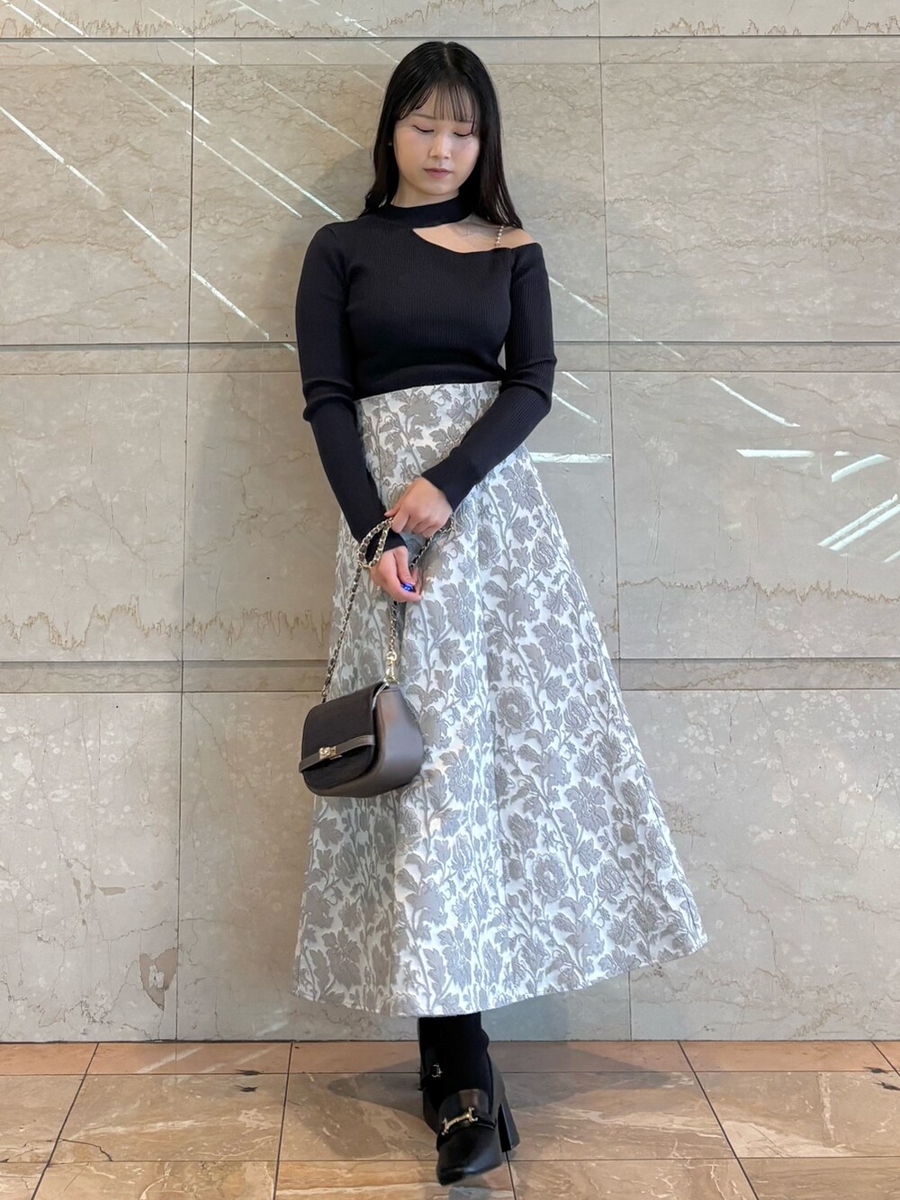 ブラウン系のハンドバッグ、ブラック系のブーツ、グレー系のニット/セーターを着用したレディースの冬コーディネートの2枚目の写真