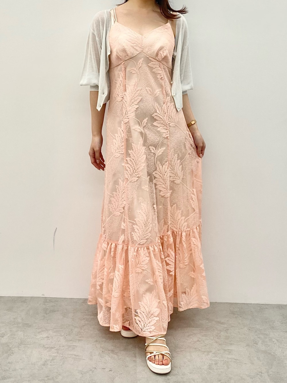 オレンジ系のワンピース、ホワイト系のサンダル、ホワイト系のカーディガン/ボレロを着用したレディースの春コーディネートの2枚目の写真