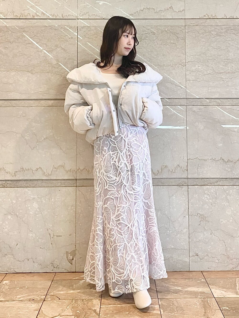 ピンク系のスカート、ホワイト系のニット/セーター、ホワイト系のダウンジャケット/コートを着用したレディースの冬コーディネートの4枚目の写真