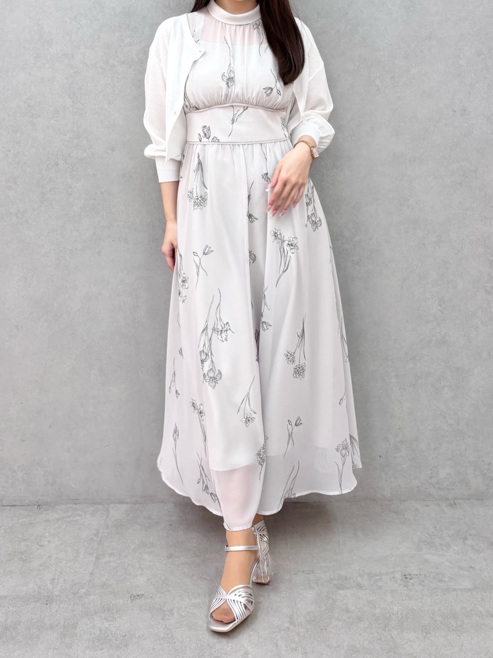 グレー系のワンピース、シルバー系のサンダル、ホワイト系のカーディガン/ボレロを着用したレディースの春コーディネートの2枚目の写真