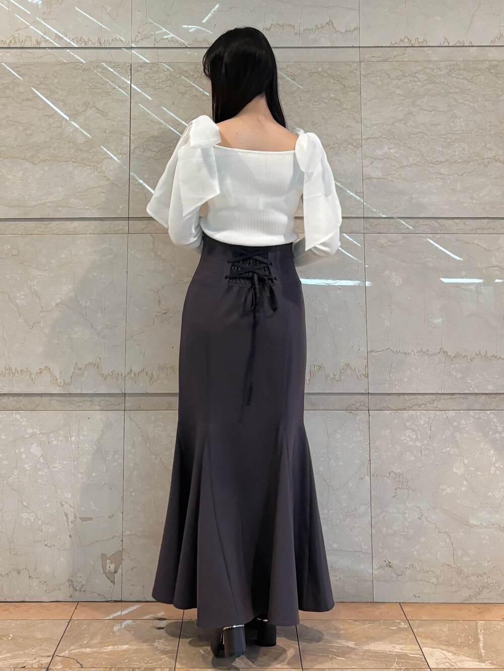 グレー系のスカート、ブラウン系のブーツ、ホワイト系のニット/セーターを着用したレディースの冬コーディネートの2枚目の写真