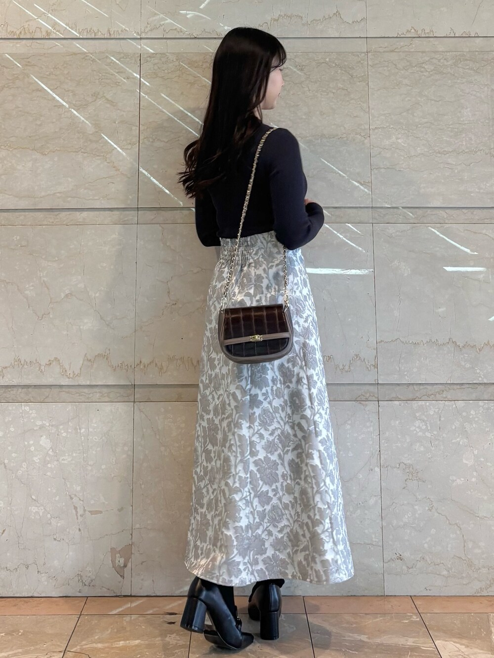 ブラウン系のハンドバッグ、ブラック系のブーツ、グレー系のニット/セーターを着用したレディースの冬コーディネートの4枚目の写真