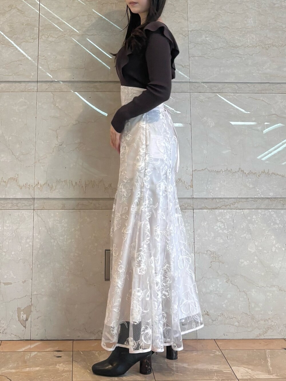 ブラウン系のニット/セーター、ブラック系のブーツ、ピンク系のスカートを着用したレディースの冬コーディネートの2枚目の写真