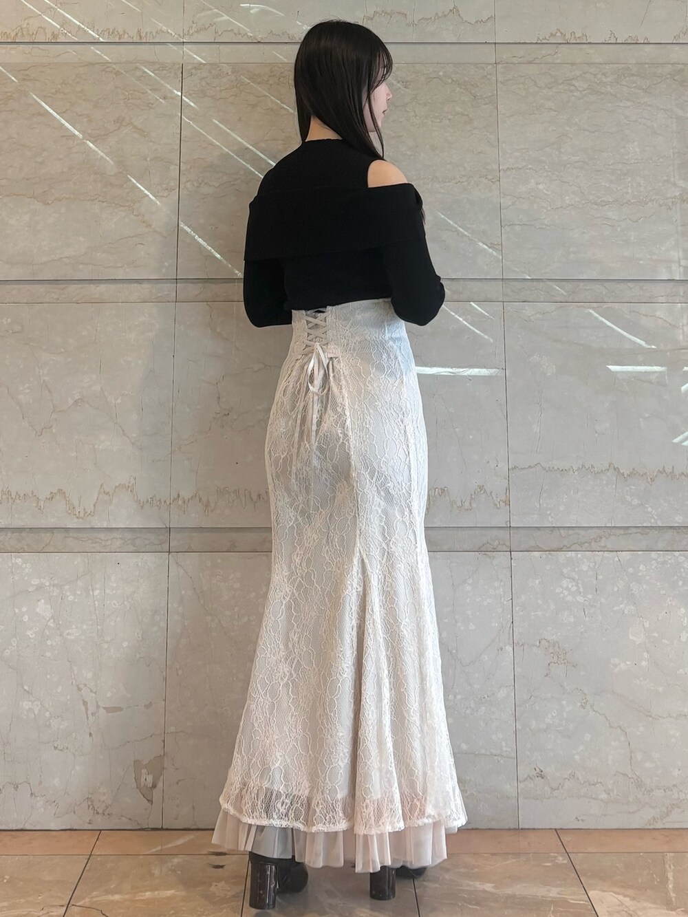 ホワイト系のスカート、ブラック系のブーツ、ブラック系のニット/セーターを着用したレディースの冬コーディネートの3枚目の写真