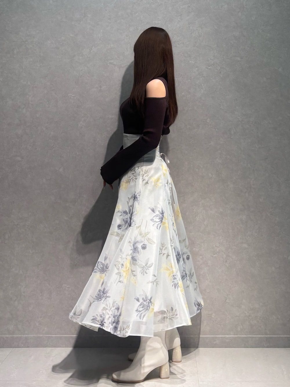 グリーン系のスカート、ブラウン系のニット/セーター、ホワイト系のブーツを着用したレディースの冬コーディネートの4枚目の写真