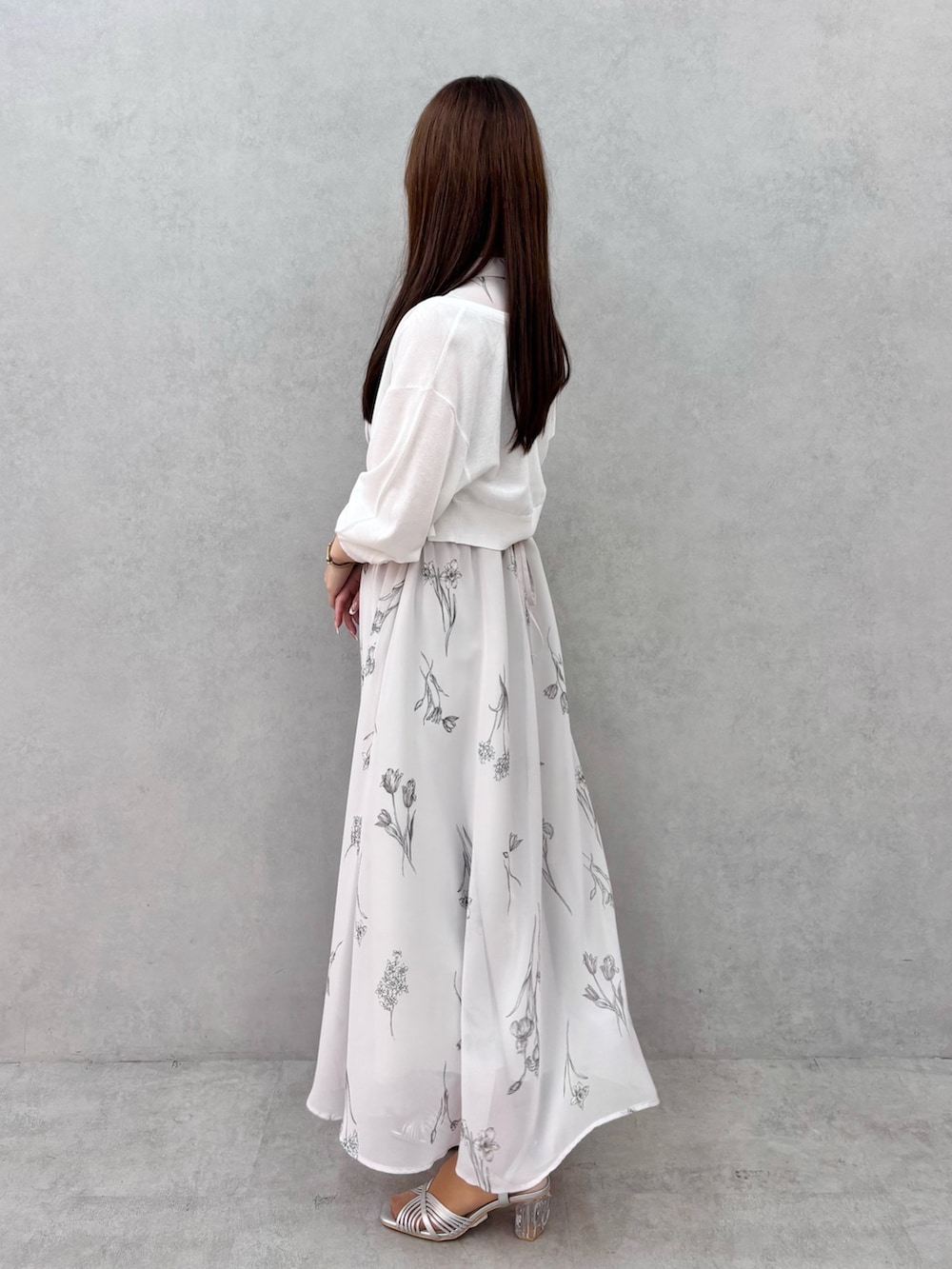 グレー系のワンピース、シルバー系のサンダル、ホワイト系のカーディガン/ボレロを着用したレディースの春コーディネートの3枚目の写真