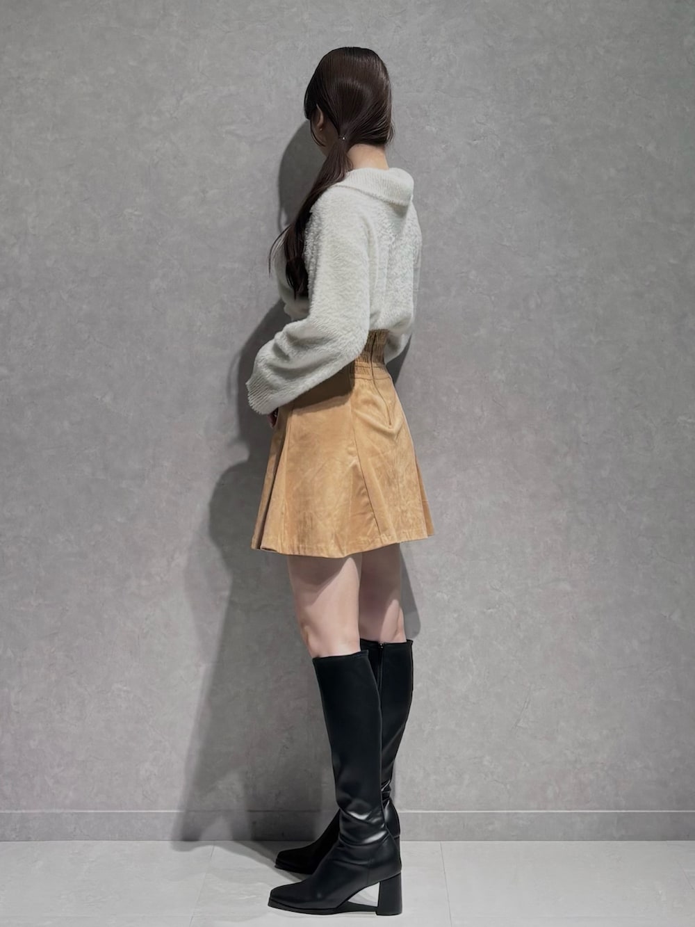 イエロー系のスカート、ホワイト系のニット/セーター、ブラック系のブーツを着用したレディースの秋コーディネートの4枚目の写真