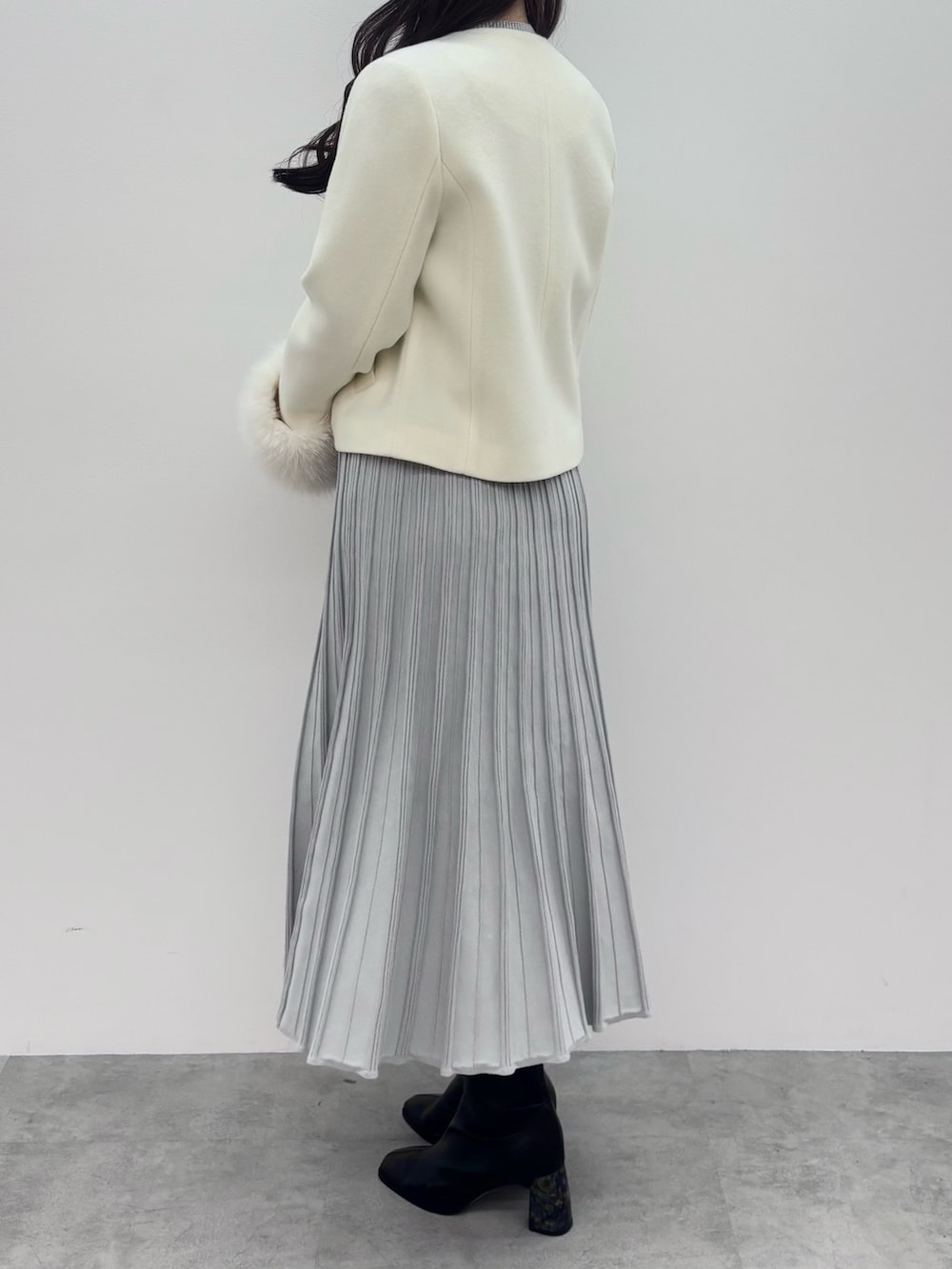 ブラック系のブーツ、ホワイト系のその他アウター、グレー系のワンピースを着用したレディースの冬コーディネートの4枚目の写真