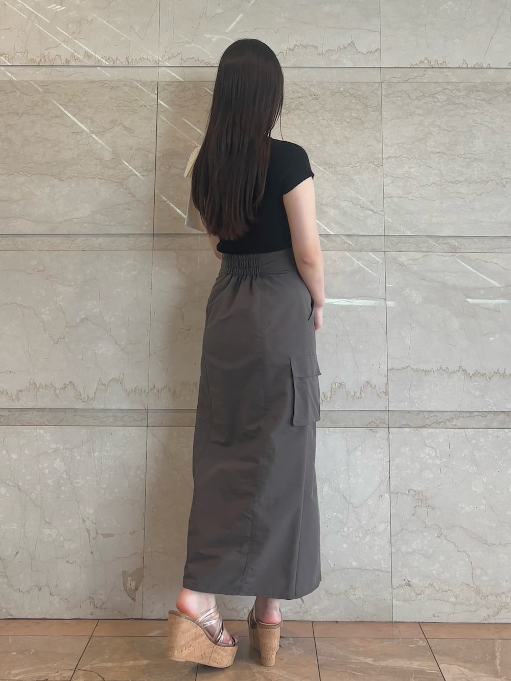 ブラウン系のスカート、ブラウン系のサンダル、ブラック系のニット/セーターを着用したレディースの夏コーディネートの5枚目の写真