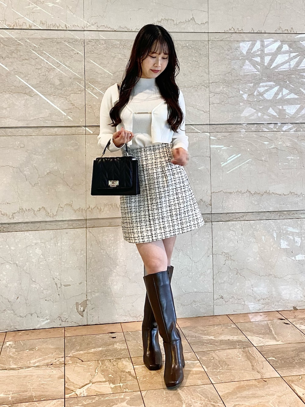 ホワイト系のニット/セーター、ホワイト系のスカート、ブラック系のショルダーバッグを着用したレディースの秋コーディネートの2枚目の写真
