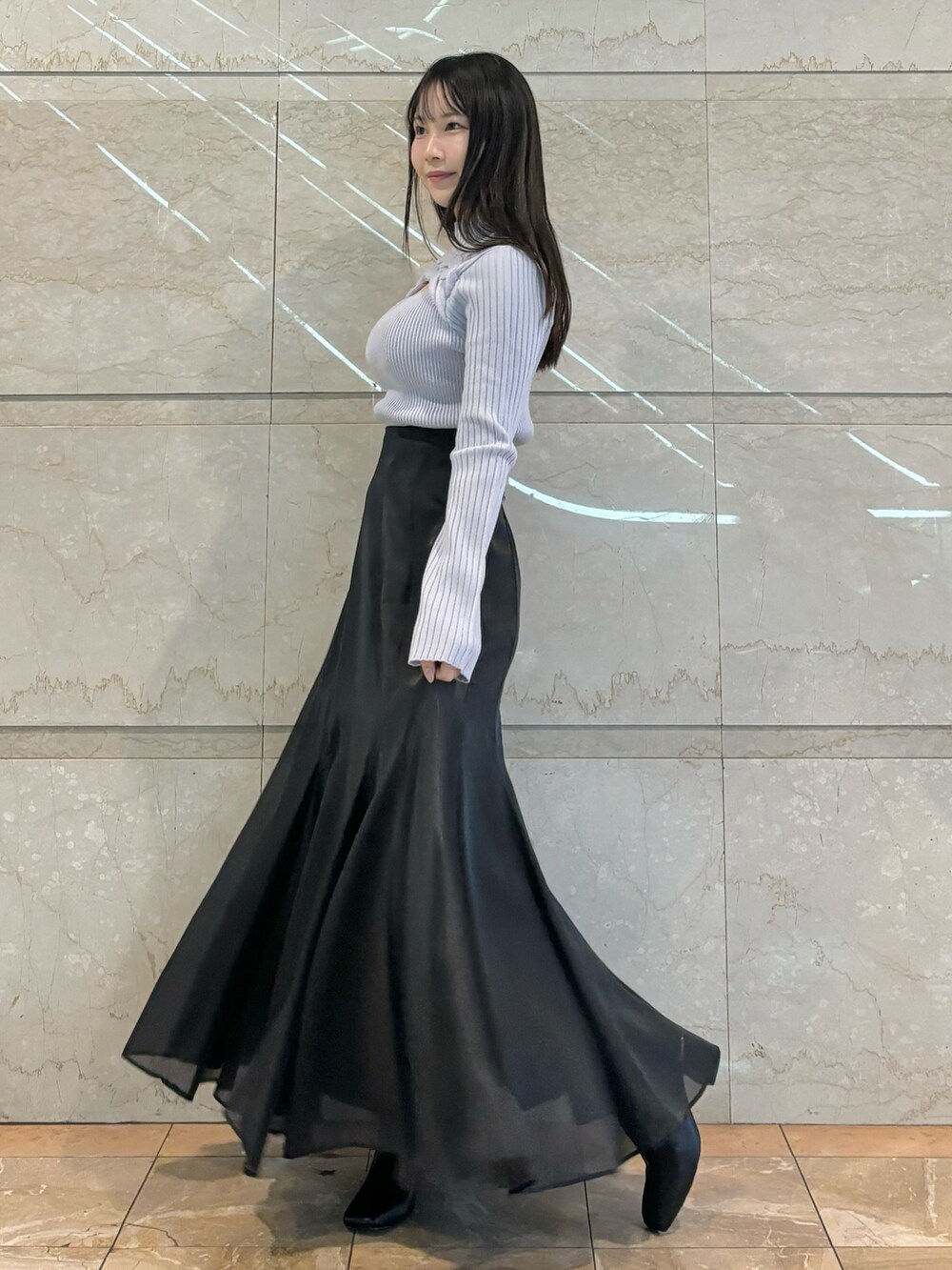 ブラック系のスカート、ブラック系のブーツ、ブルー系のニット/セーターを着用したレディースの秋コーディネートの3枚目の写真