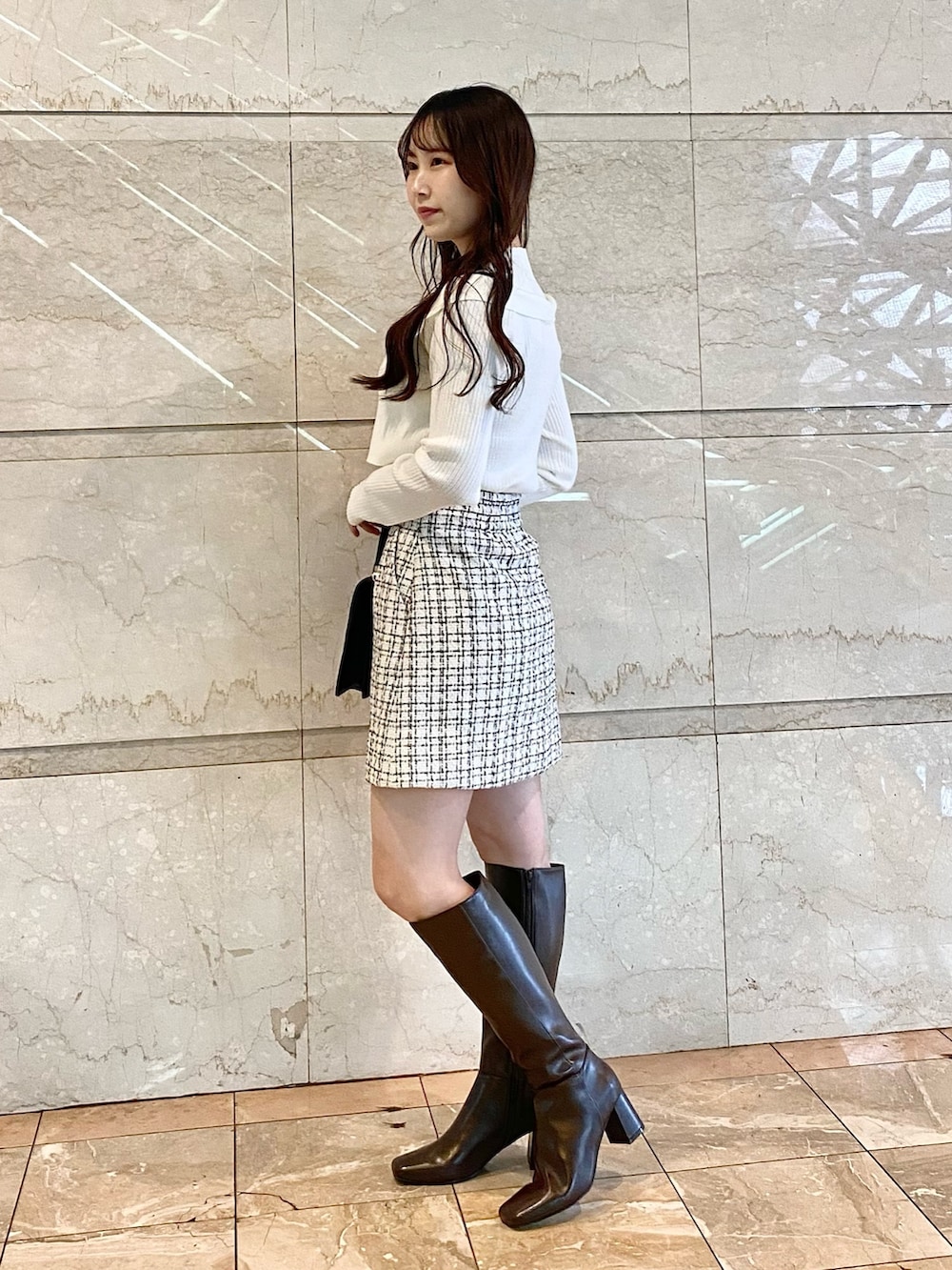 ホワイト系のニット/セーター、ホワイト系のスカート、ブラック系のショルダーバッグを着用したレディースの秋コーディネートの3枚目の写真