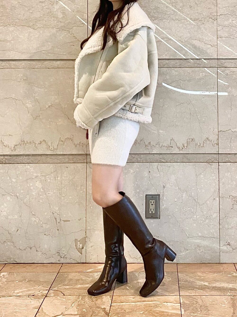 ホワイト系のムートンコート、ホワイト系のワンピース、ブラウン系のブーツを着用したレディースの秋コーディネートの4枚目の写真