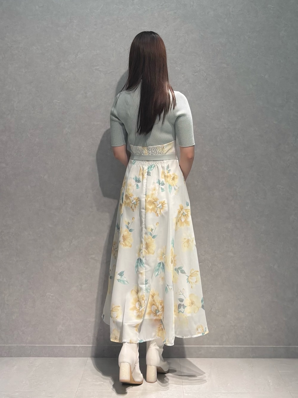 グリーン系のワンピース、ホワイト系のブーツ、ブラウン系のハンドバッグを着用したレディースの春コーディネートの5枚目の写真