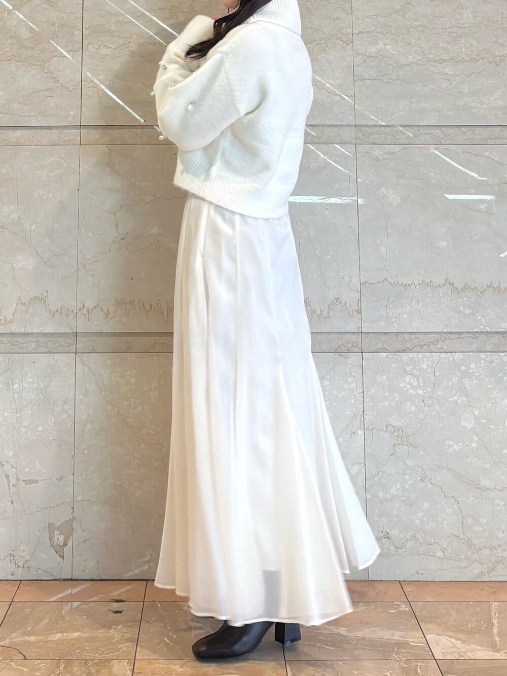 ホワイト系のスカート、ブラウン系のブーツ、ホワイト系のニット/セーターを着用したレディースの冬コーディネートの3枚目の写真