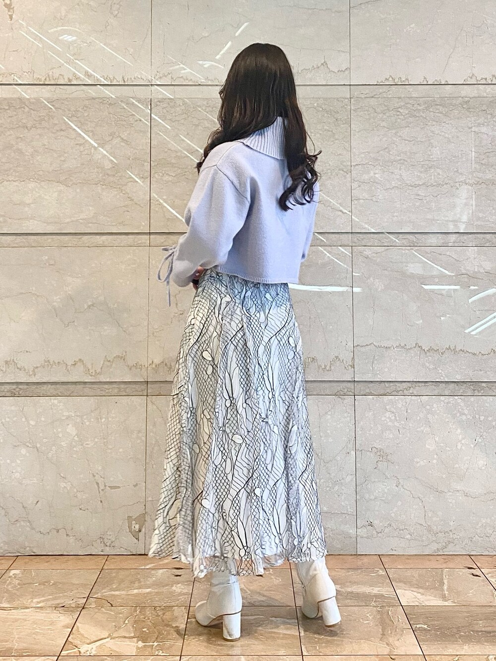 ホワイト系のスカート、ブルー系のニット/セーター、ホワイト系のブーツを着用したレディースの冬コーディネートの3枚目の写真