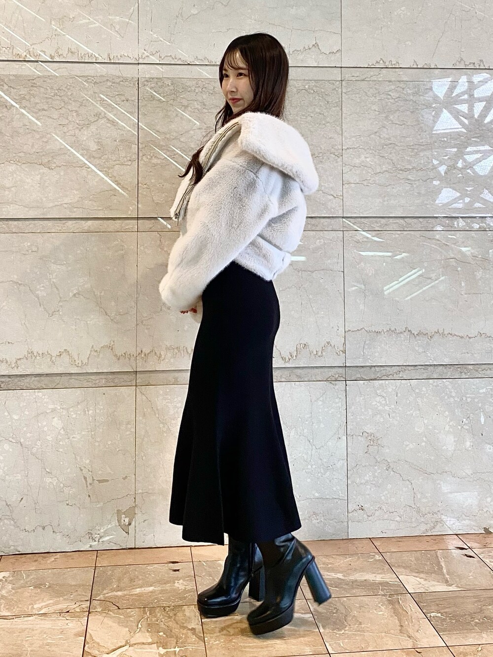 ホワイト系のその他アウター、ブラック系のワンピース、ブラック系のブーツを着用したレディースの秋コーディネートの2枚目の写真