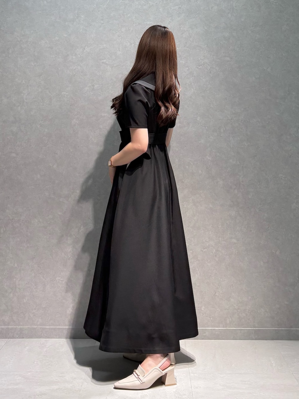 ブラック系のワンピース、ホワイト系のパンプス、ホワイト系のハンドバッグを着用したレディースの春コーディネートの5枚目の写真