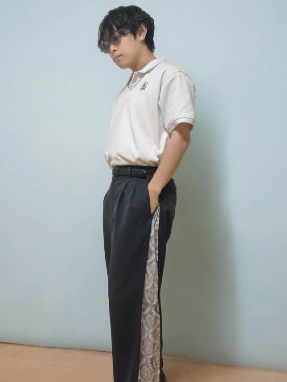 ホワイト系のポロシャツ、ブラック系のスラックス、ブラック系のローファーを着用したメンズの春コーディネートの3枚目の写真