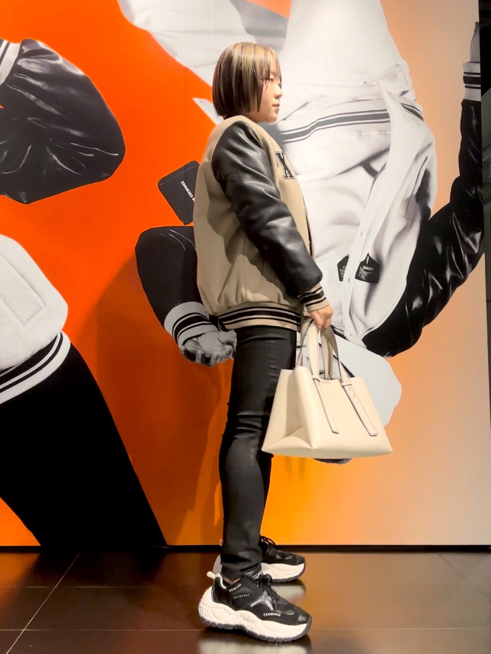 ベージュ系のトートバッグ、ブラック系のスウェット、ベージュ系のブルゾンを着用したレディースの秋コーディネートの2枚目の写真