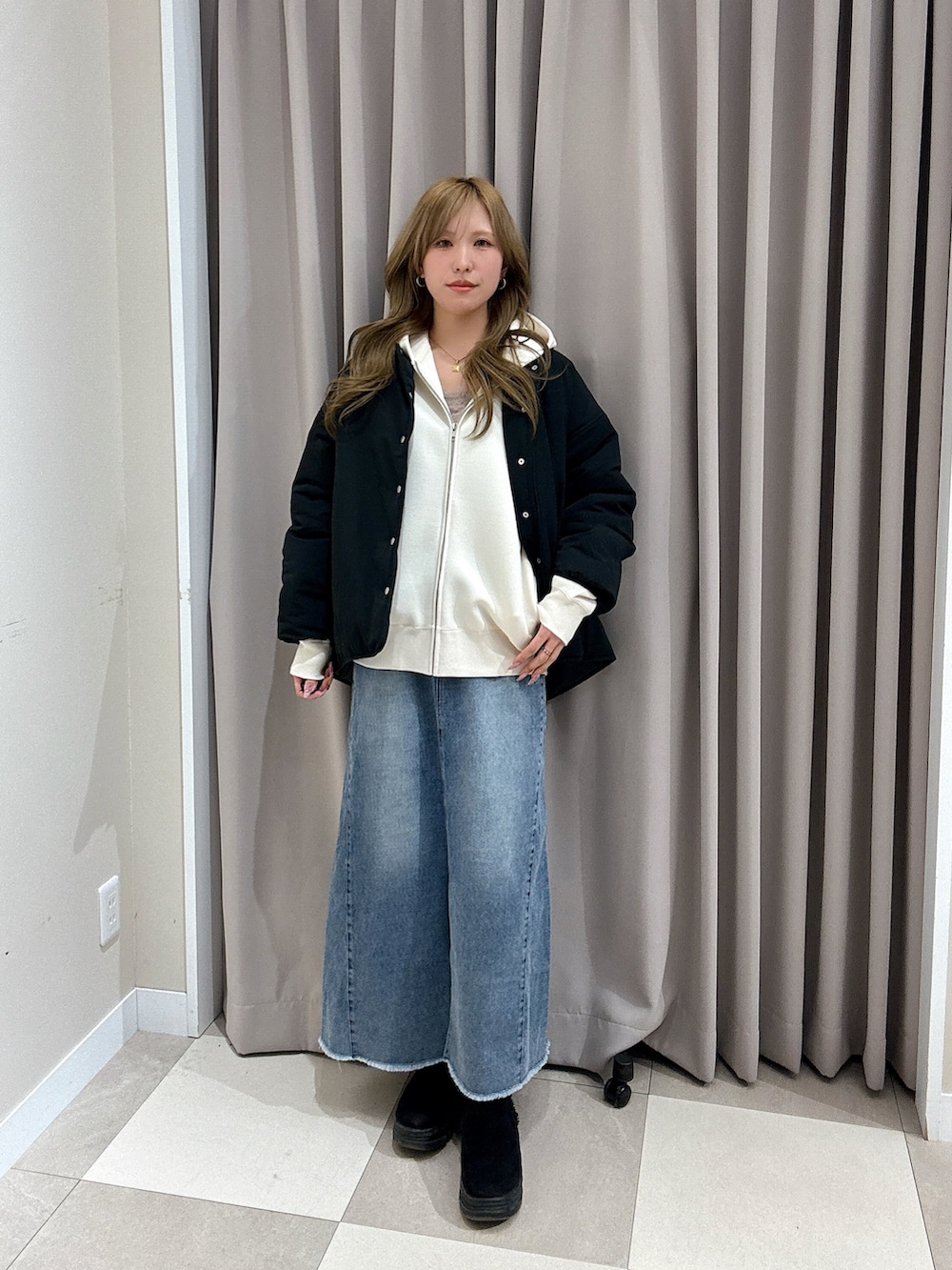 ブルー系のスカート、ブラック系のダウンジャケット/コート、ホワイト系のパーカーを着用したレディースの冬コーディネートの2枚目の写真