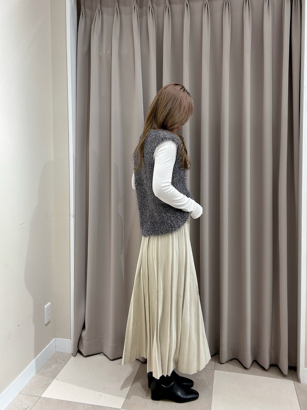 ベージュ系のスカート、グレー系のベストを着用したレディースの冬コーディネートの3枚目の写真