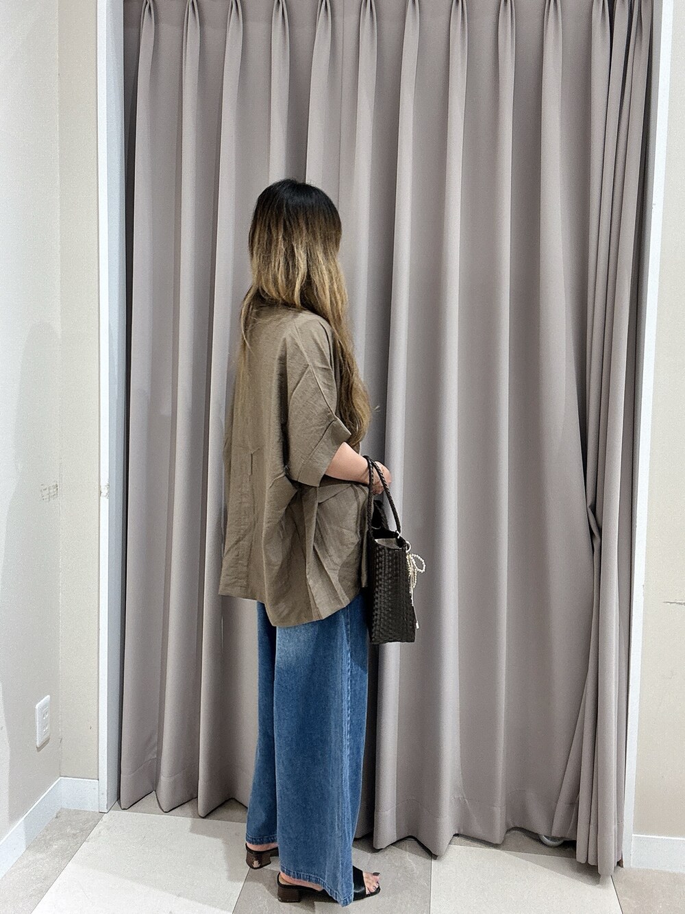 ブルー系のデニムパンツ、ホワイト系のニット/セーター、ブラウン系のその他アウターを着用したレディースの夏コーディネートの2枚目の写真