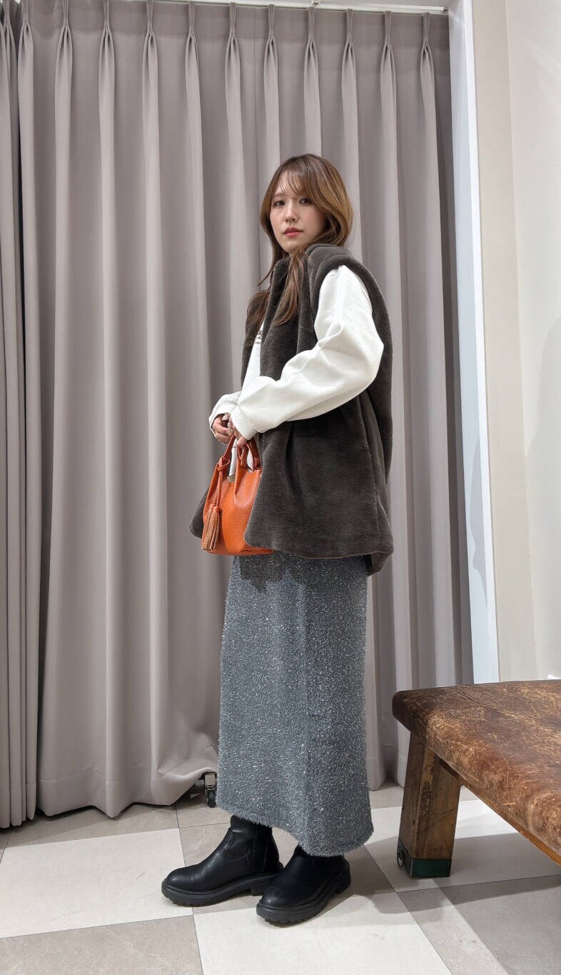 オレンジ系のショルダーバッグ、グレー系のスカート、ブラウン系のその他アウターを着用したレディースの冬コーディネートの2枚目の写真