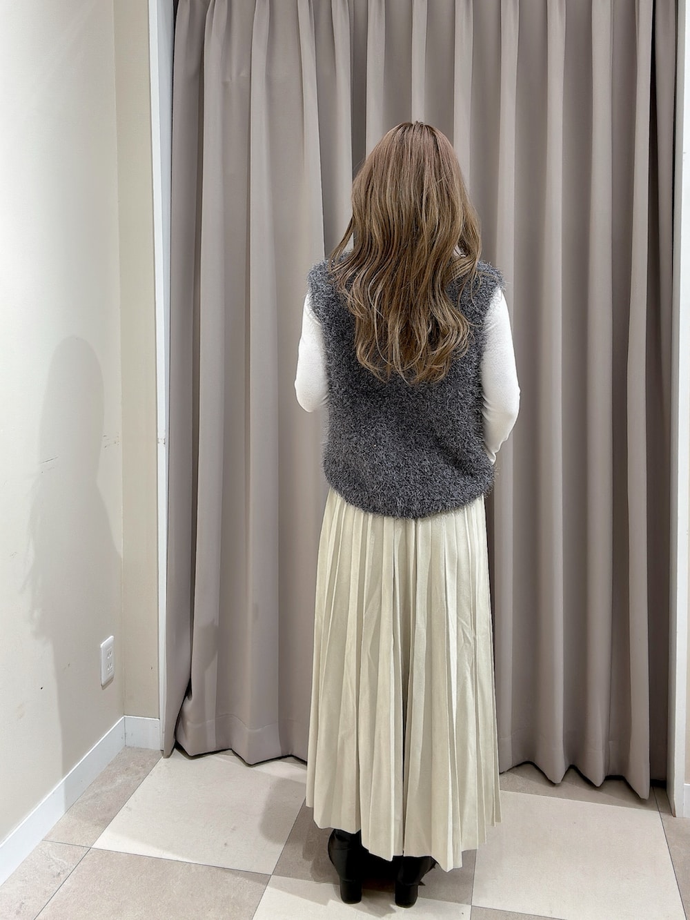 ベージュ系のスカート、グレー系のベストを着用したレディースの冬コーディネートの4枚目の写真