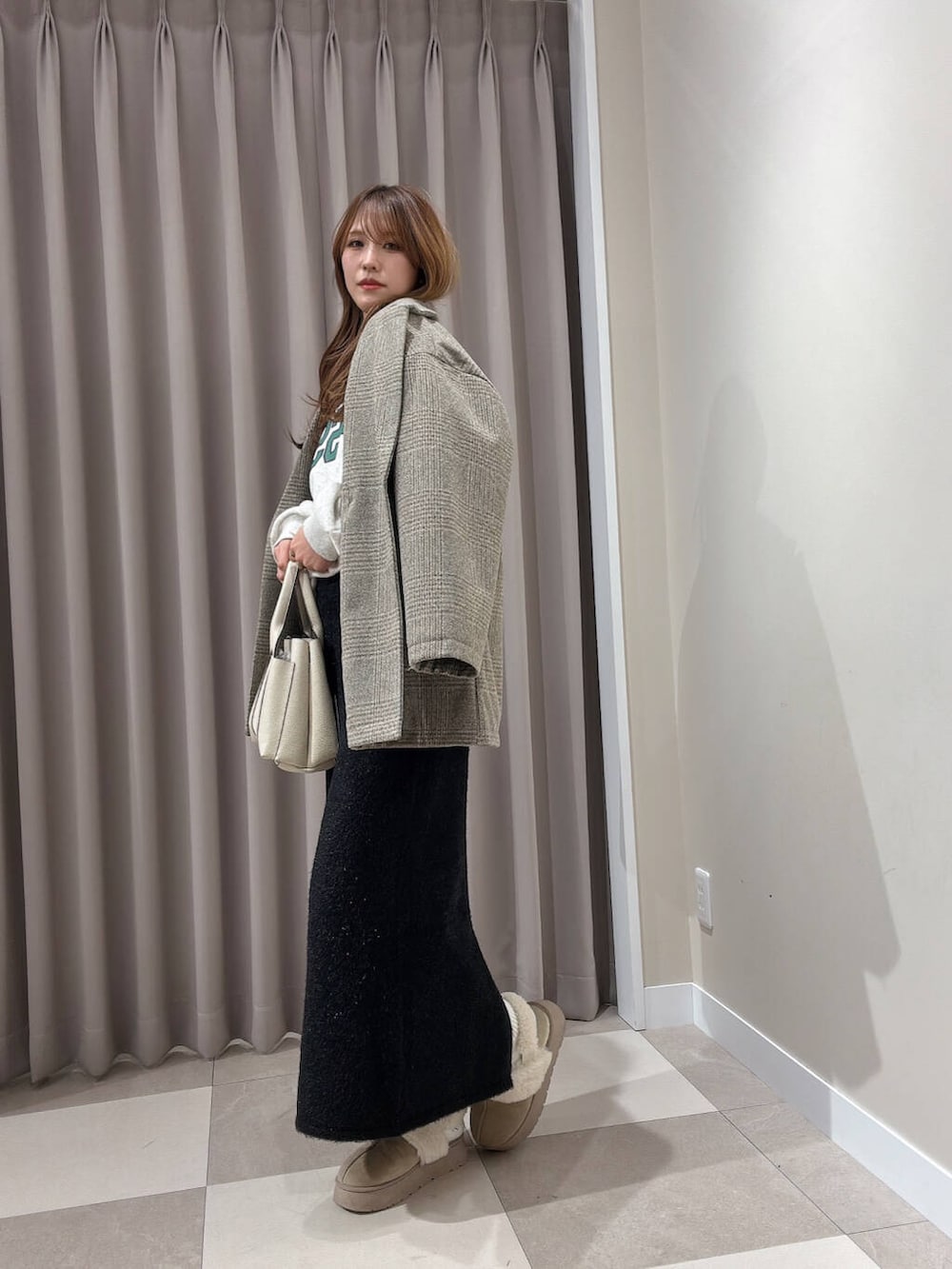 ホワイト系のトートバッグ、グレー系のスウェット、ブラック系のスカートを着用したレディースの冬コーディネートの2枚目の写真