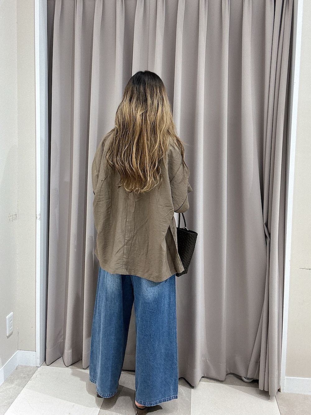 ブルー系のデニムパンツ、ホワイト系のニット/セーター、ブラウン系のその他アウターを着用したレディースの夏コーディネートの3枚目の写真