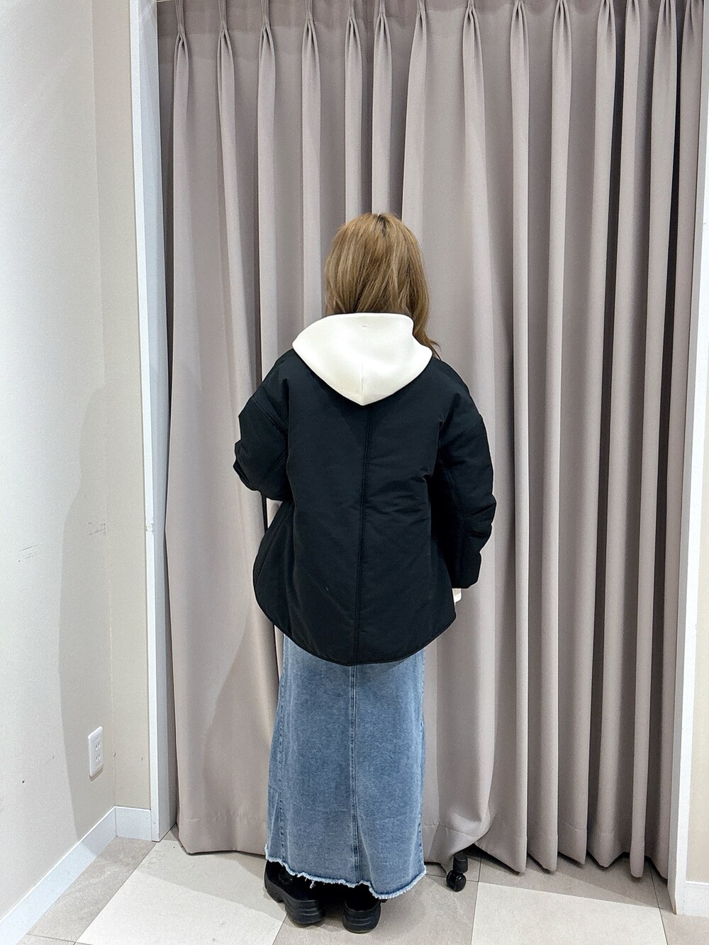 ブルー系のスカート、ブラック系のダウンジャケット/コート、ホワイト系のパーカーを着用したレディースの冬コーディネートの4枚目の写真