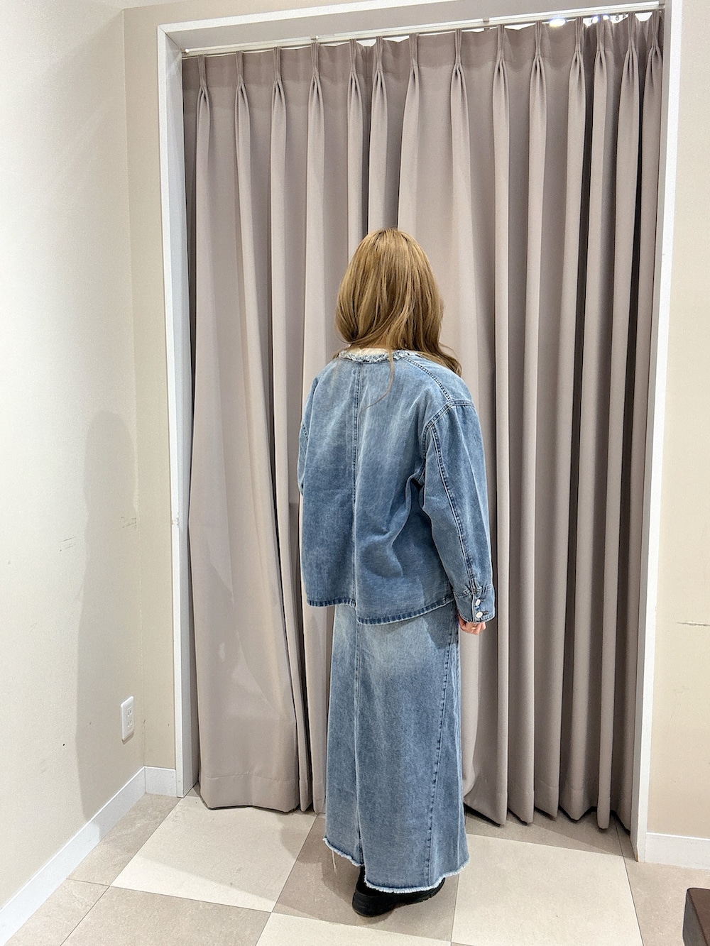 ブルー系のスカート、ホワイト系のニット/セーター、ブルー系のデニムジャケットを着用したレディースの冬コーディネートの2枚目の写真