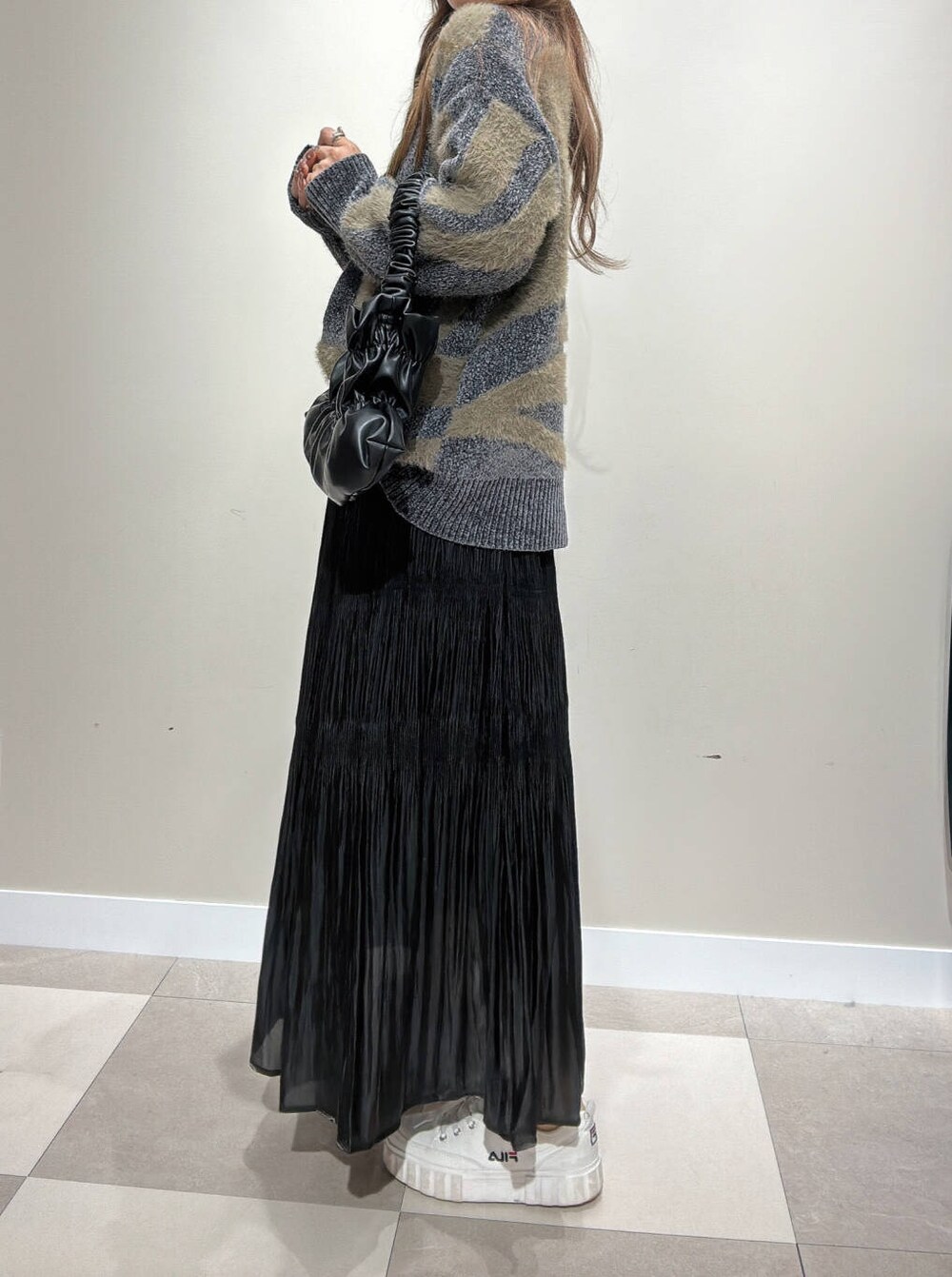 ブラック系のハンドバッグ、ブラック系のスカート、グレー系のニット/セーターを着用したレディースの秋コーディネートの2枚目の写真