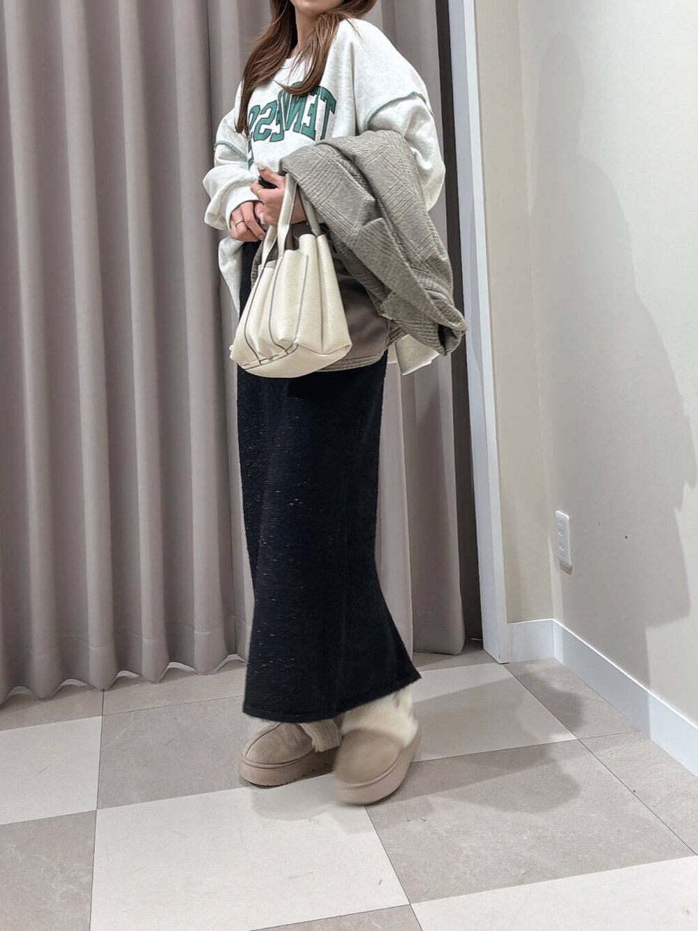 ホワイト系のトートバッグ、グレー系のスウェット、ブラック系のスカートを着用したレディースの冬コーディネートの3枚目の写真
