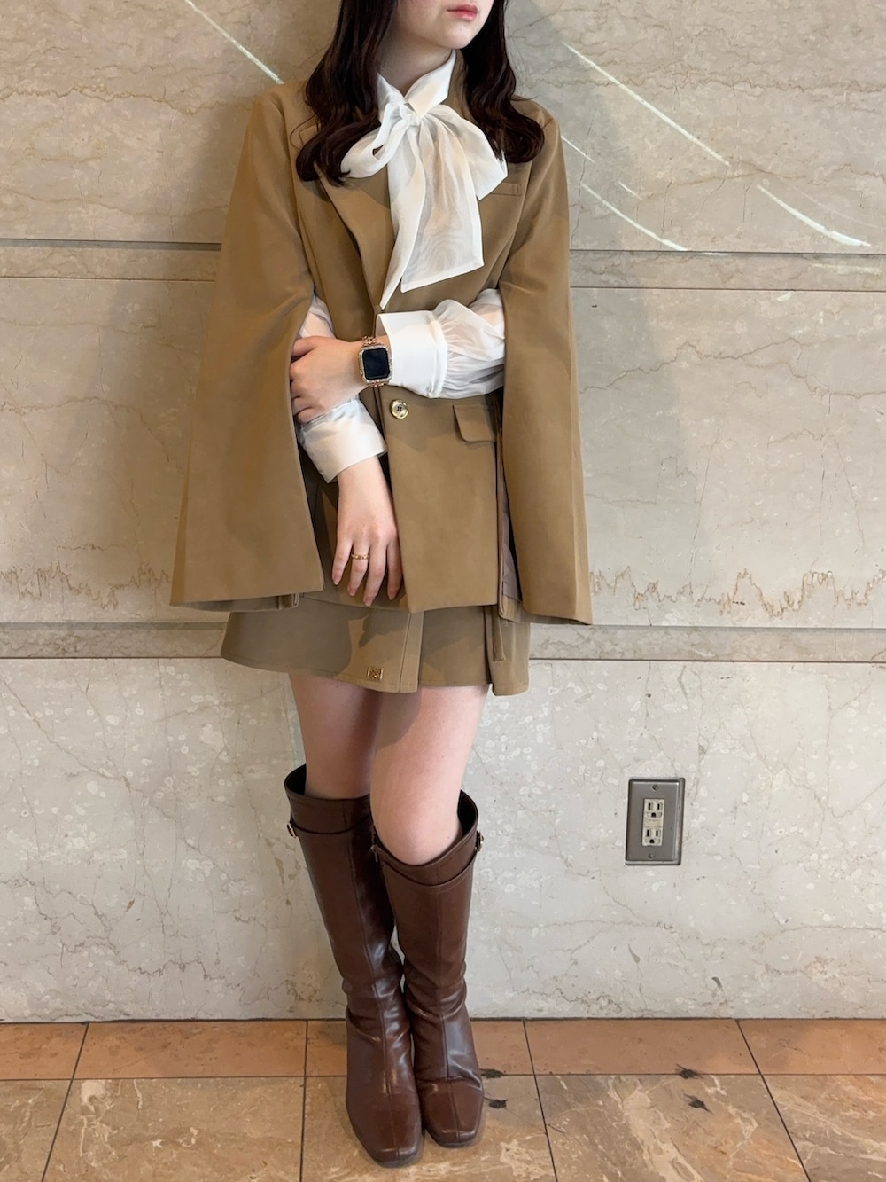 ベージュ系のテーラードジャケット、ベージュ系のスカート、ブラウン系のブーツを着用したレディースの冬コーディネートの2枚目の写真