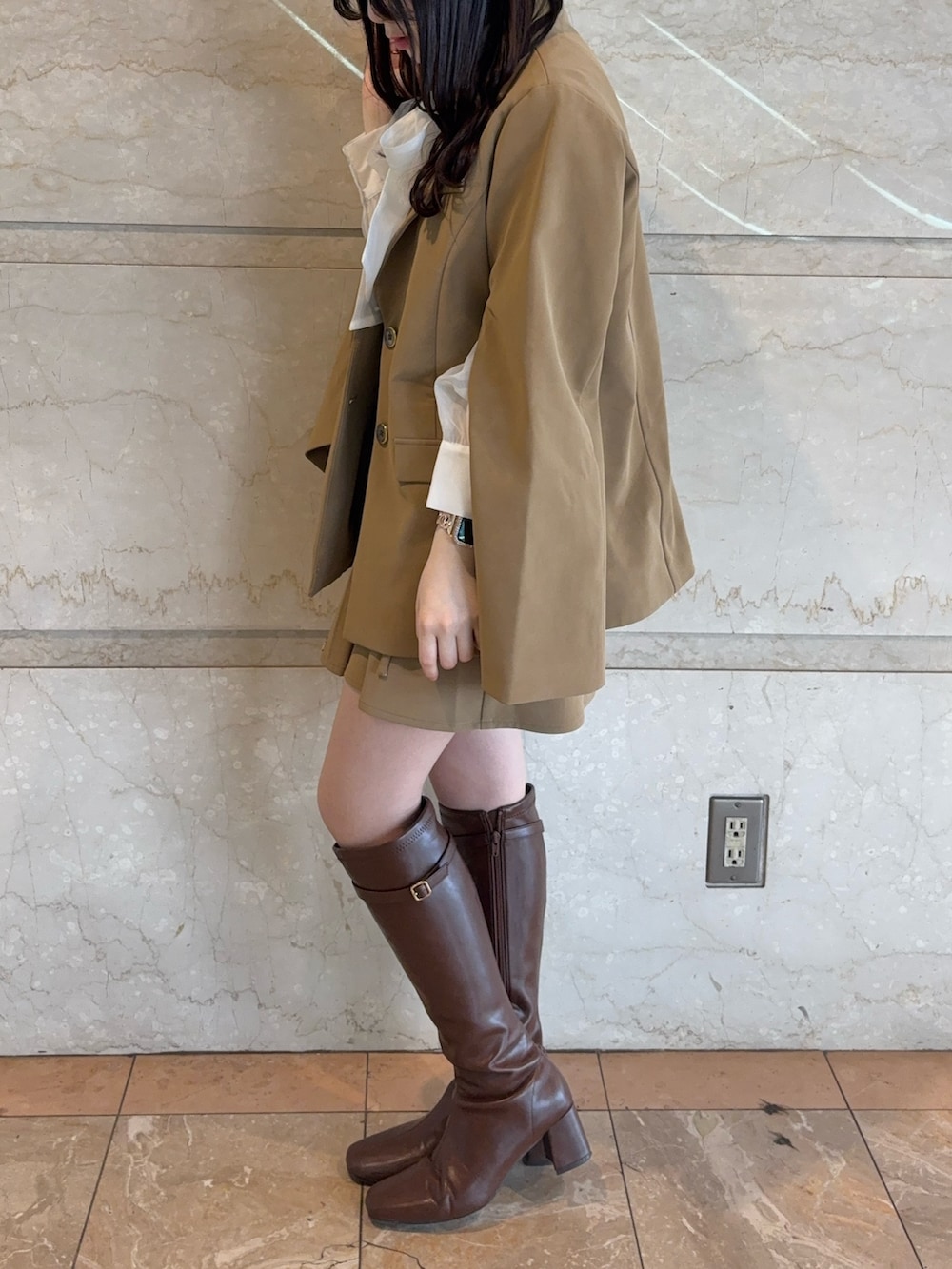 ベージュ系のテーラードジャケット、ベージュ系のスカート、ブラウン系のブーツを着用したレディースの冬コーディネートの3枚目の写真