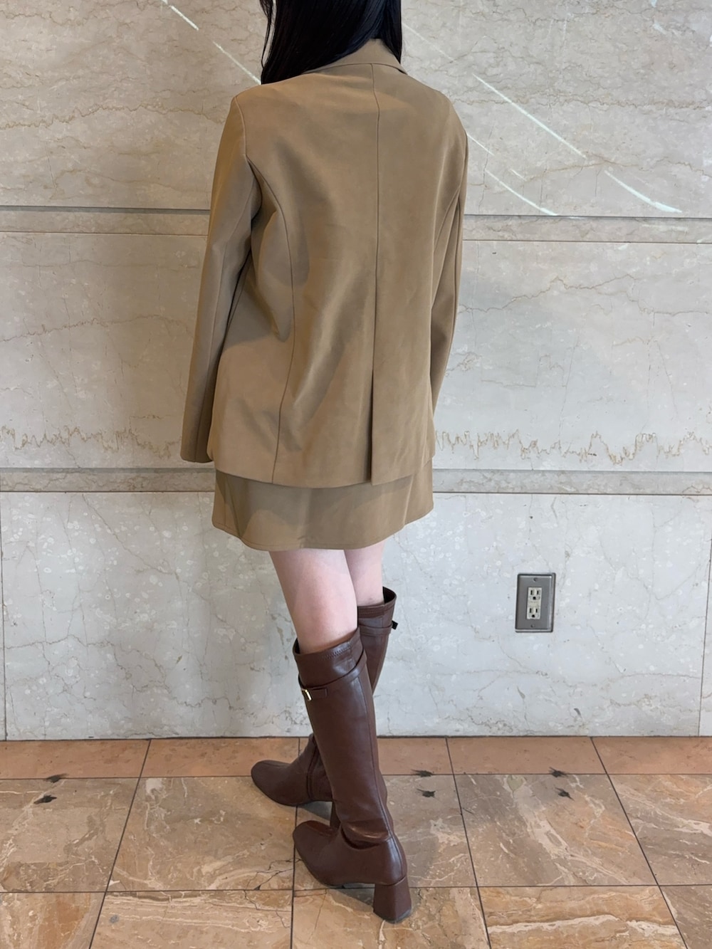 ベージュ系のテーラードジャケット、ベージュ系のスカート、ブラウン系のブーツを着用したレディースの冬コーディネートの4枚目の写真